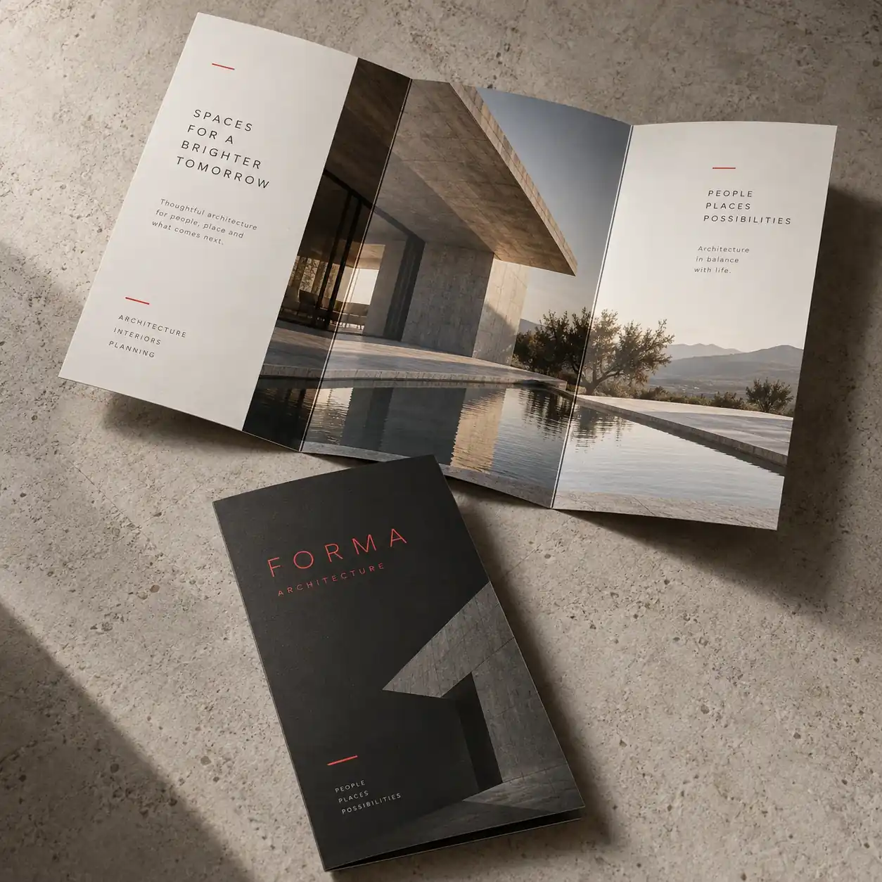 Printed brochures shown as a physical product in charcoal, red and warm white