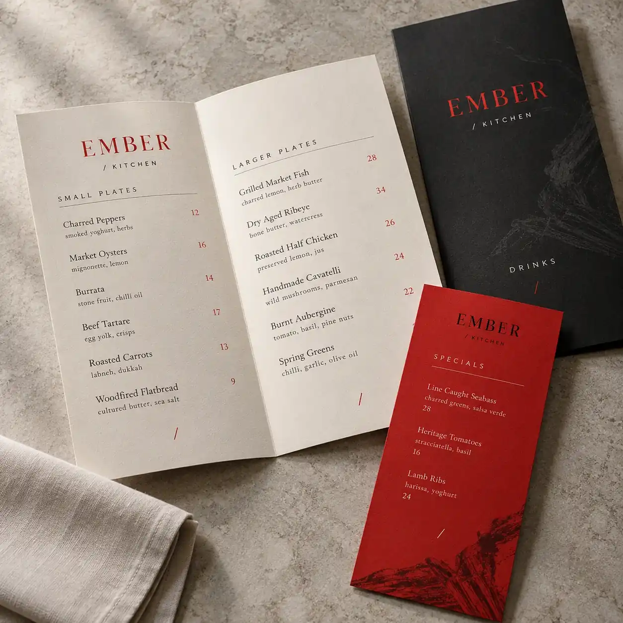 Printed menus shown as a physical product in charcoal, red and warm white